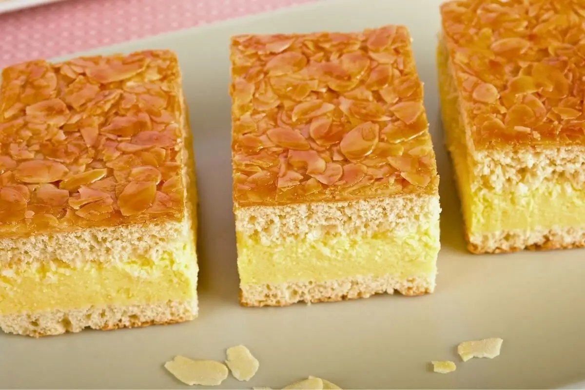 Warum heißt der Bienenstich Bienenstich? Drei Stücke Bienenstich-Kuchen auf Teller nebeneinander